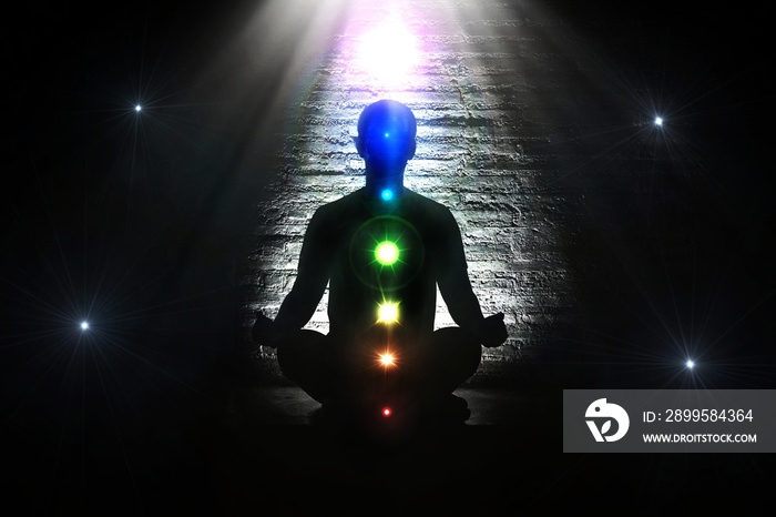 Meditating human in lotus pose. Yoga illustration.Colorful 7 chakras and aura glow in darkness space.