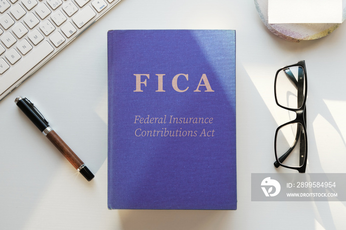 FICA or Federal Insurance Contributions Act book illustration. Office desk table lit by evening sun. Top view, flat lay.