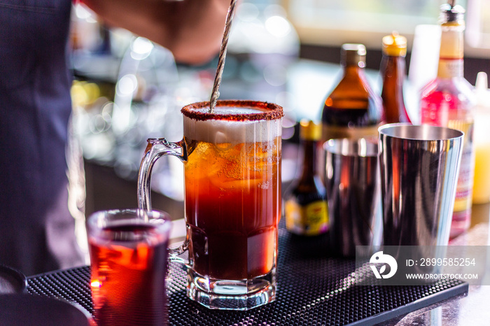 Preparación de michelada, cerveza en tarro en restaurante preparada con pepino, camarón, chile chamoy, apio y Clamato