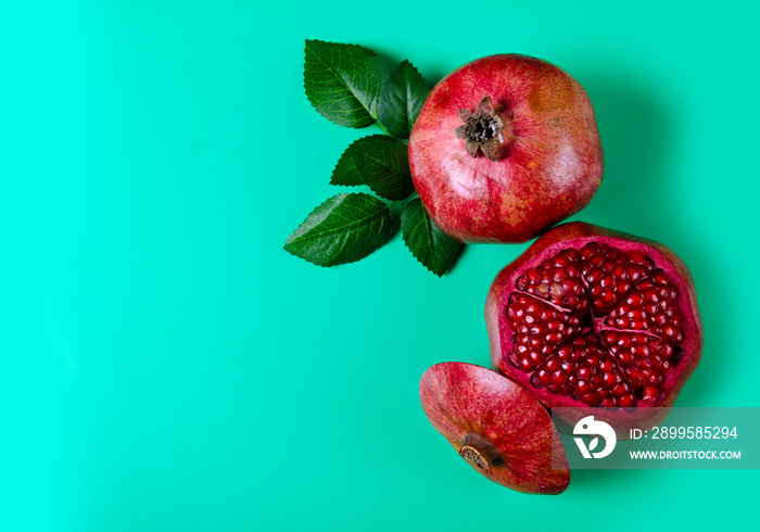 Pomegranate red fruit on green background, top view