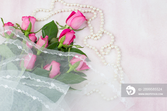 a bouquet of pink roses wrapped in a veil