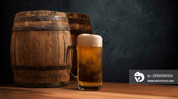 Oktoberfest beer barrel and beer glasses with wheat and hops on wooden table