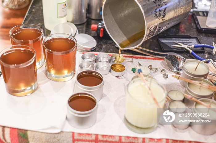 Creative occupation of candle making showing the pouring of liquid wax into jars