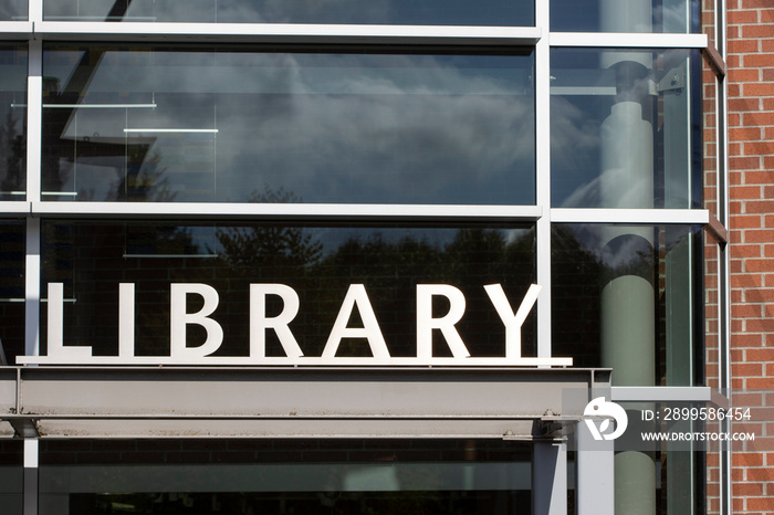 Closeup of the library sign at the entrance to a modern public library in a city.