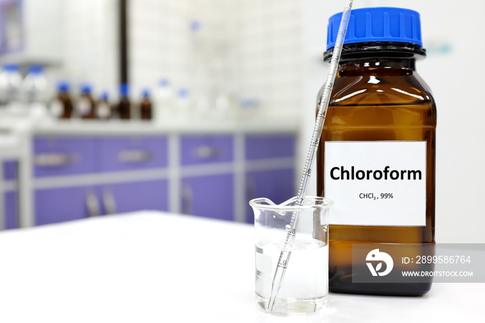 Selective focus of chloroform or trichloromethane liquid chemical in glass amber bottle inside a chemistry laboratory with copy space.