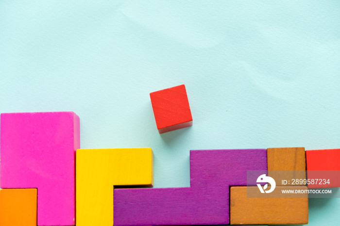 Different colorful shapes wooden blocks on blue background, flat lay. Geometric shapes in different colors, top view. Concept of creative, logical thinking or problem solving. Copy space.