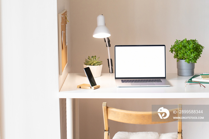 Laptop with blank white screen on office desk interior. Stylish rose gold workplace mockup table view.