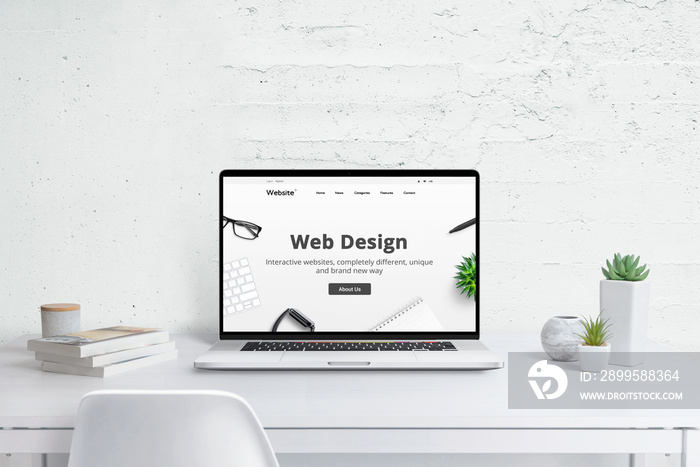 Web design studio creative concept. Modern laptop computer with company web site, flat design theme concept. White wooden desk with plants and books