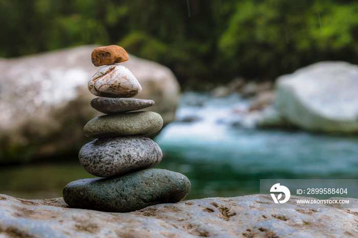 Rocks stacked in balance in a peaceful rainforest on the side of a river in a national park of Costa Rica