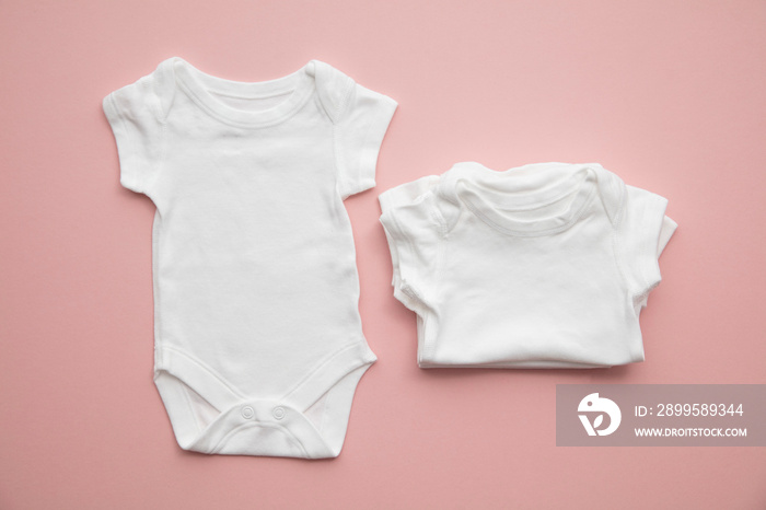 Cute baby white body suit layout on a pastel pink background