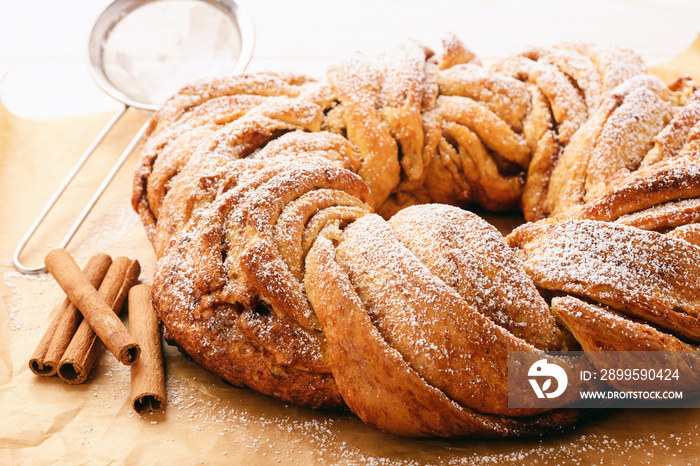 Braided cinnamon roll cake on wooden background.