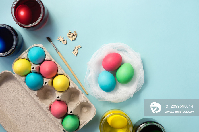 DIY egg dying set, tray of colored easter eggs on pastel blue background. Flat lay.