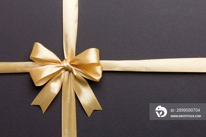 Top view of gold ribbon rolled and yellowbow isolated on colored background. Flat lay with copy space