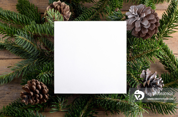 Christmas 5x5 card mockup template on natural fir twigs on wooden background. Design element for Christmas and New Year congratulation, rsvp, thank you, greeting or invitation card, sale