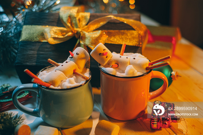 a mug with hot chocolate on a wooden table with a marshmallow man who is resting in a mug