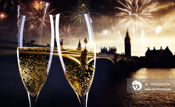 celebrating new year’s eve in the city - toasting with champagne glasses in front of Big Ben- holiday lights and fireworks in the background