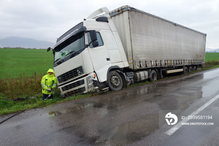 Real event. Car accident. The truck lies in a ditch after the road accident over raining day in autumn time. Rescuers help with car accident.