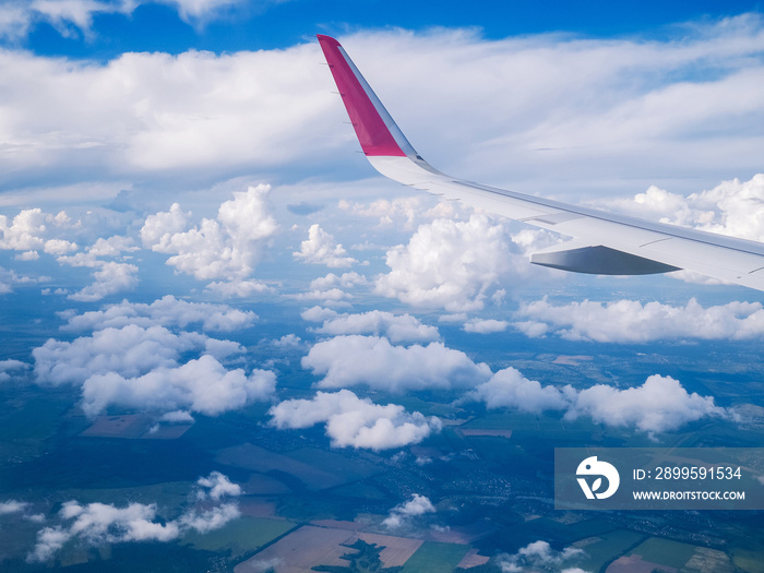 View from airplane window: wing  plane in cloudy sky.