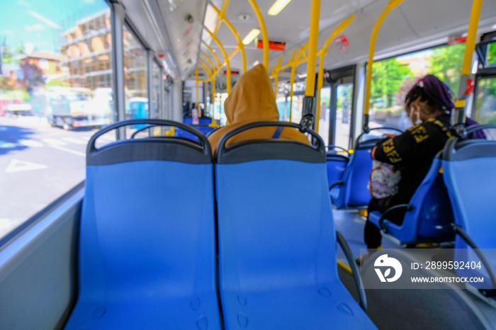 Defocused people on the bus. Empty blue seats in a bus close-up. Public urban transportation