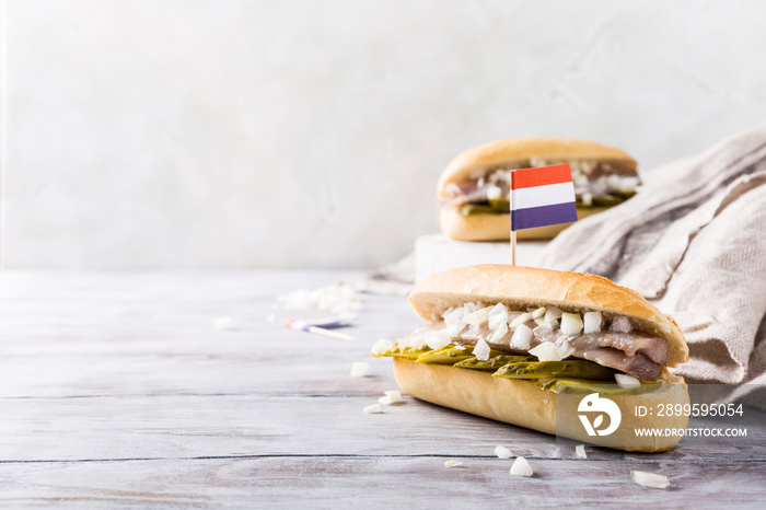 Traditional dutch snack, seafood sandwich with herring, onions and pickled cucumber. Broodje haring. Copy space. With flag of Netherlands.