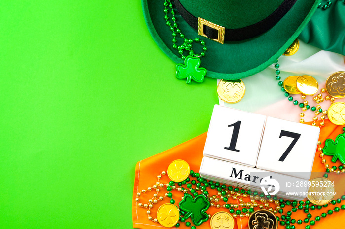 The luck of the Irish meme and Happy St Patricks day concept theme with a calendar, leprechaun hat, beads necklace and gold coins on the Ireland flag isolated on green background with copy space