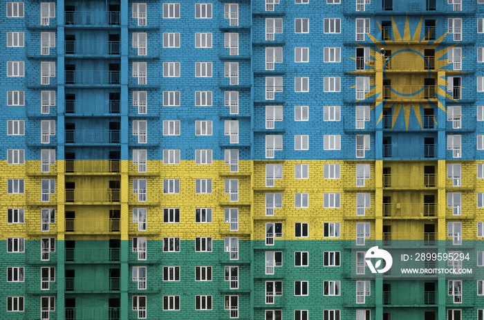 Rwanda flag depicted in paint colors on multi-storey residental building under construction. Textured banner on brick wall background