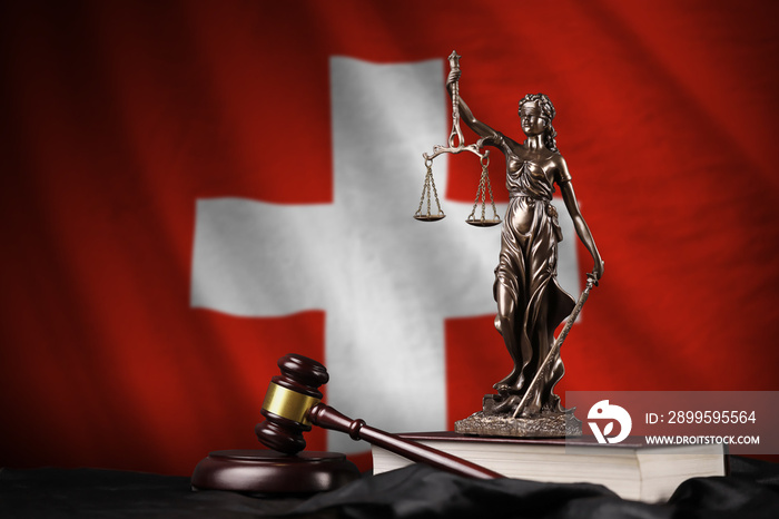 Switzerland flag with statue of lady justice, constitution and judge hammer on black drapery. Concept of judgement and guilt