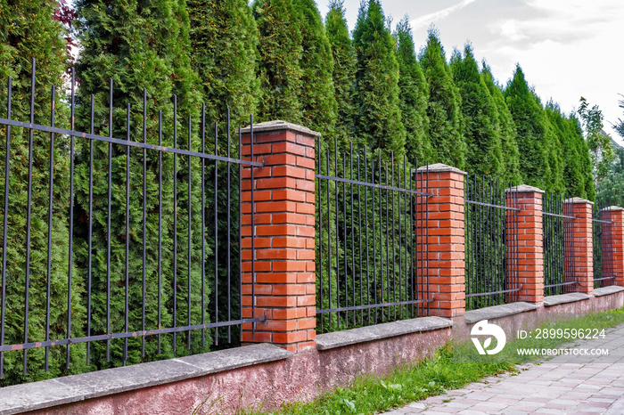 High fence with brick columns. Black Railings and brick wall