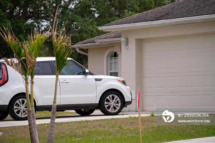 Vehicle parked in front of wide garage double door on paved driveway of typical contemporary american home