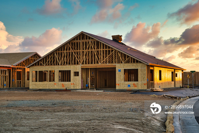 New construction of framing and roofing of residential home in California with beautiful sunset sky