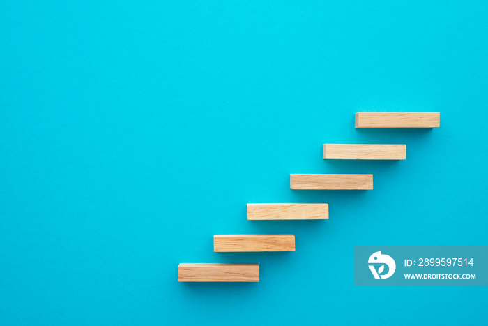 Flat lay of wooden blocks in shape of staircase step on blue background with copy space. Growth or development step by step for successful in business financial or education concept.