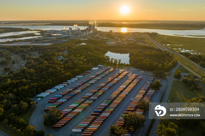 Large cargo container yard with many freight containers and big factory manufactory structure. Production and distribution of produced goods