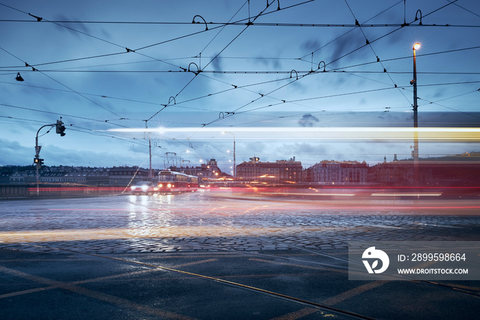 Light trails of tram in Prague downtown. Busy road intersection in city at rainy evening.  .