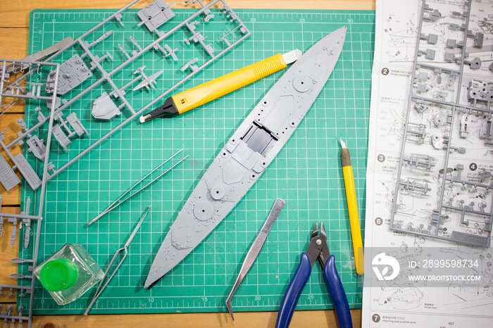 building plastic model WW2 battleship with tools on cutting pad closeup.