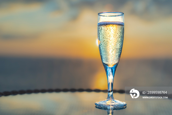 Vue d’une flute à champagne avec un coucher de soleil dans le sillage d’un navire de croisière.