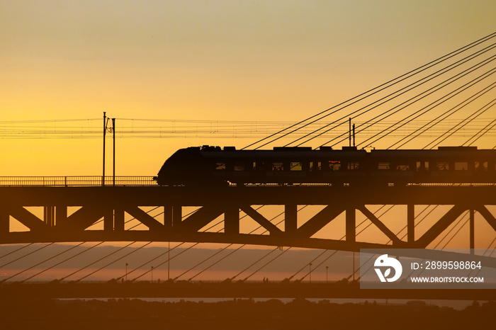 Traffic on the railway bridge. Train at sunset.