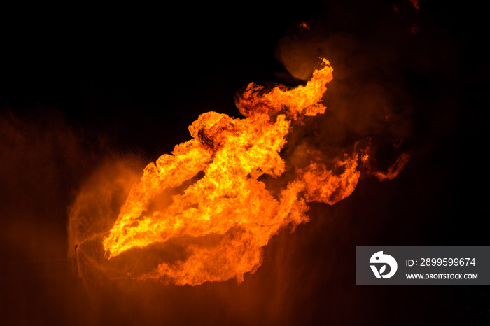 Well testing operation (flaring) of an oil and gas drilling rig. Burning huge gas flame controlled by the deluge system