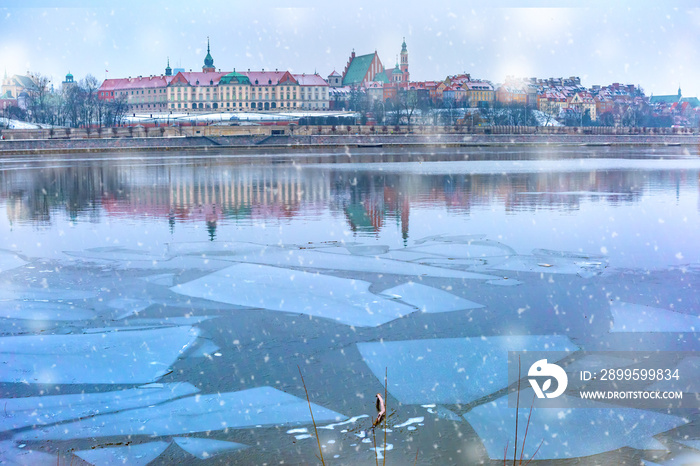 Old Town with reflection in the Vistula River during snowy evening blue hour, Warsaw, Poland.