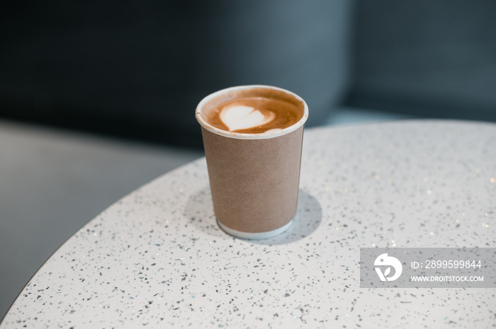 latte coffee on a paper cup served on white table at cafe​