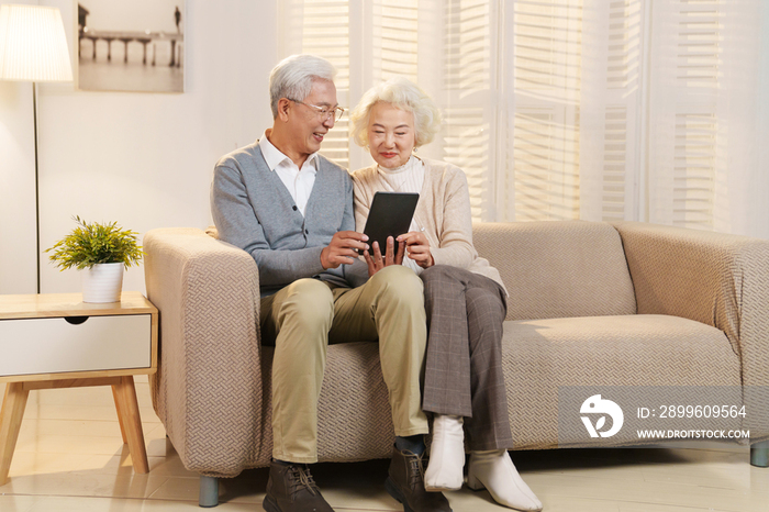 老年夫妇坐在沙发上使用平板电脑