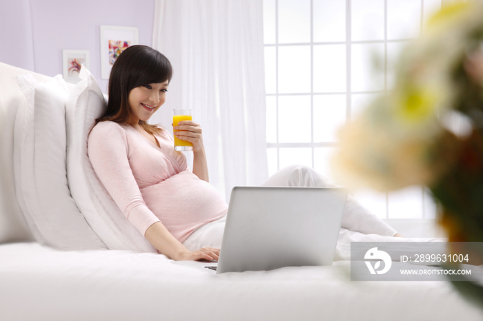孕妇坐在床上看电脑