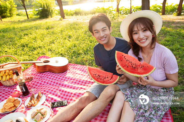 青年情侣坐在公园里吃西瓜