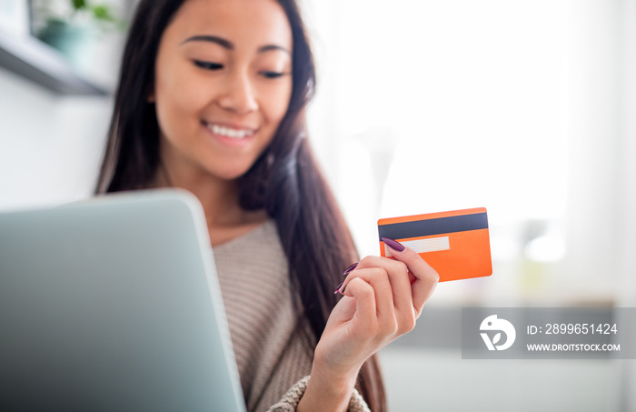 Asian girl making online payment using laptop for shopping at home