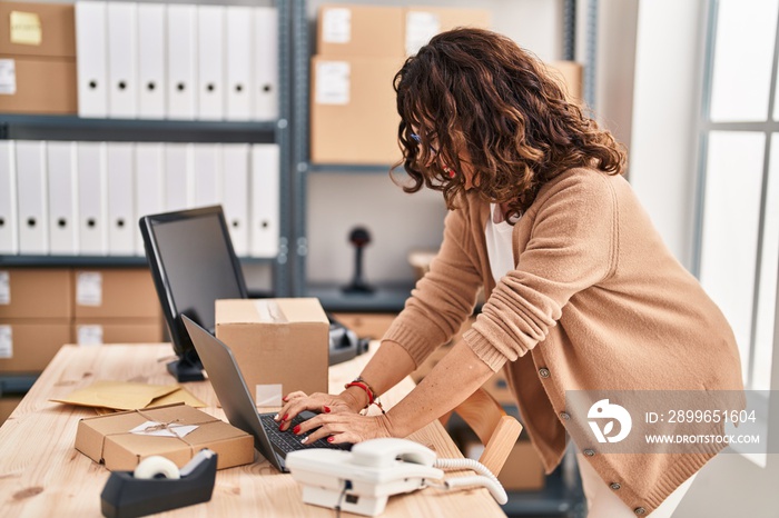 Middle age hispanic woman working with laptop at ecommerce