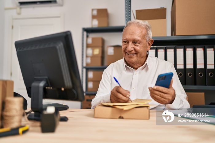 Senior man ecommerce business worker writing on package using smartphone at office