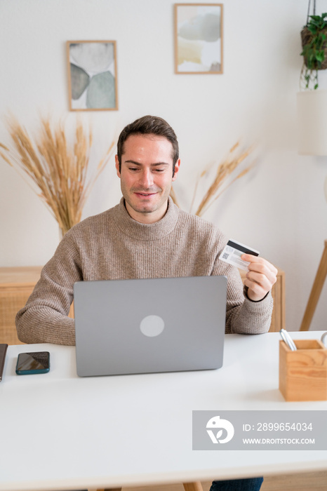 Happy man using laptop at home shopping online