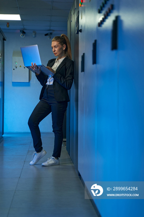 Female technician using laptop in server room