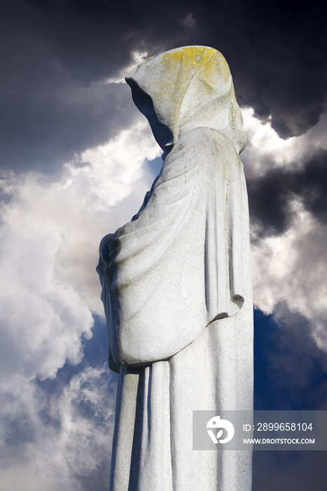 faceless monk statues against dark skies