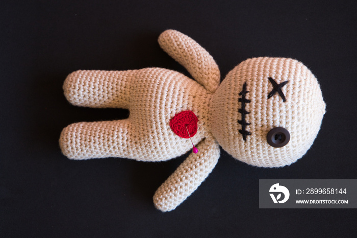 voodoo doll lying on a black background.