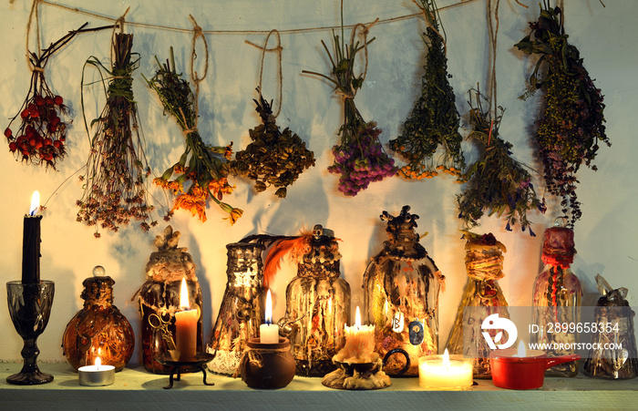 Still life with witch bottles, burning candles, healing herbs and flowers.